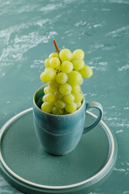 Free photo grapes in a cup high angle view on plaster and tray background