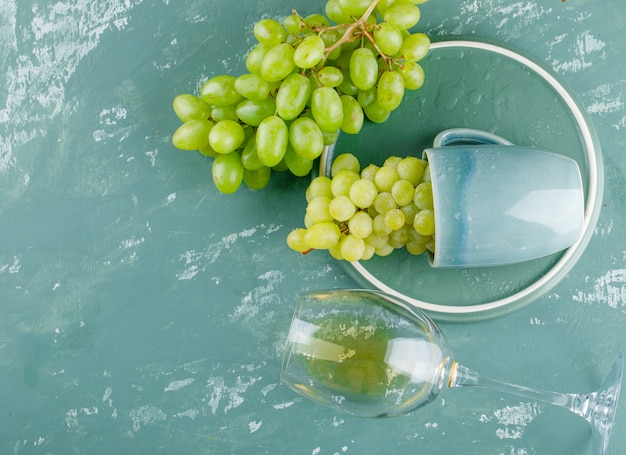 Free photo grapes in a cup with drink flat lay on plaster and tray background