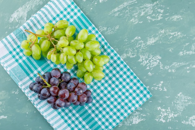 Free photo grapes flat lay on plaster and picnic cloth background