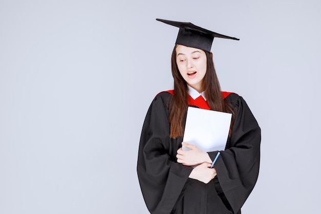 Free photo graudate student with paper and pen standing before the ceremony starts. high quality photo