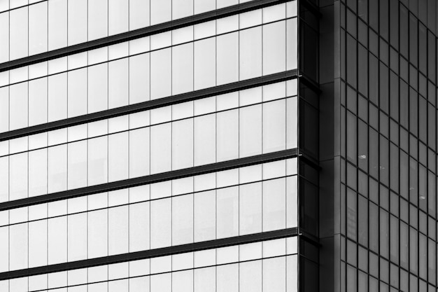 Free photo greyscale of a modern building with glass windows under sunlight