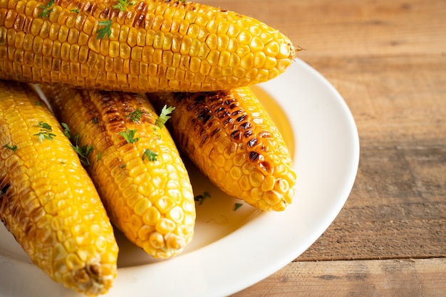 Free photo grilled corn cobs on wood background.