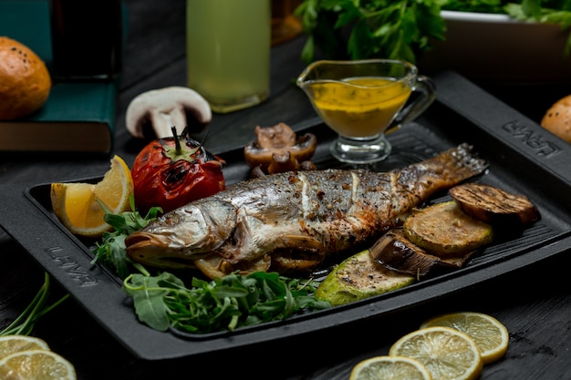 Foto gratuita barbecue di pesce alla griglia con verdure e salsa dip