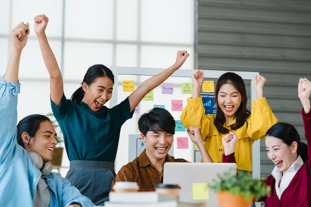 Free Photo group of asia young creative people in smart casual wear discussing business celebrate giving five after dealing feeling happy and signing contract or agreement in office. coworker teamwork concept.