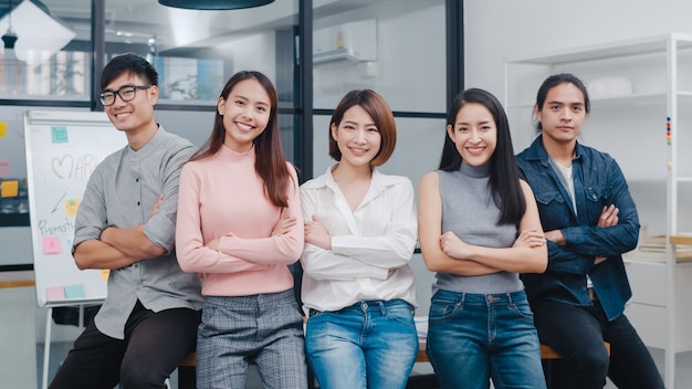 Free Photo group of asia young creative people in smart casual wear smiling and arms crossed in creative office workplace.