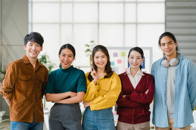 무료 사진 아시아의 젊은 창조적 인 사람들이 웃고있는 스마트 캐주얼웨어와 팔을 창조적 인 사무실 직장에서 건넜습니다. 다양한 아시아 인 남성과 여성이 스타트 업에 함께합니다. 동료 팀워크 개념입니다.