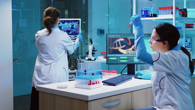 Free photo group of scientists wearing lab coat working in laboratory while examining biochemistry sample in test tube and scientific instruments