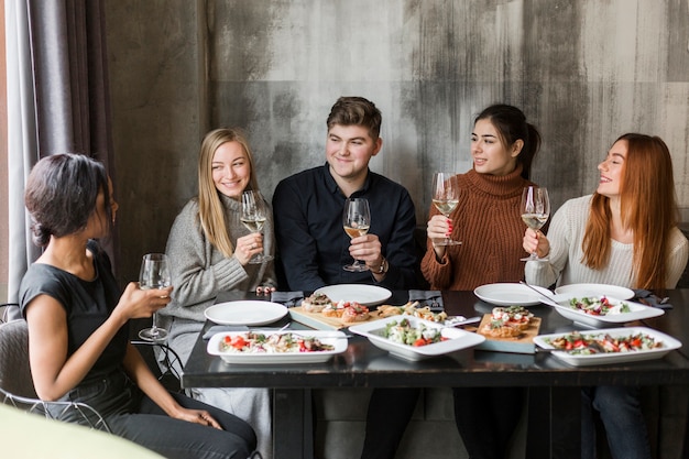 Free Photo group of young people enjoying dinner and wine together