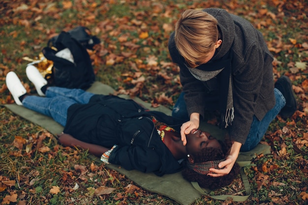 Foto gratuita guy aiuta una donna. la ragazza afro giace priva di sensi. fornire il primo soccorso nel parco