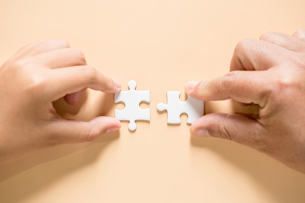 Free photo hand connecting puzzle pieces on table