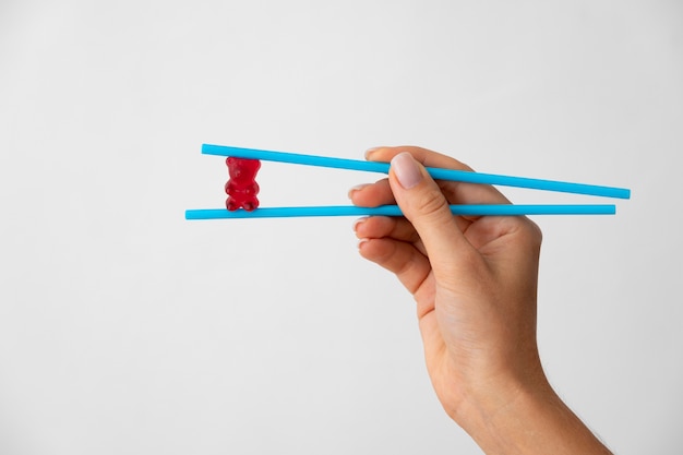 Hand holding delicious gummy bear candy with chopsticks