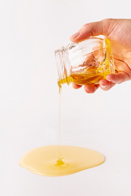 Free photo hand holding jar pouring honey