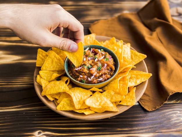 Free Photo hand holding nacho in cup of garnish