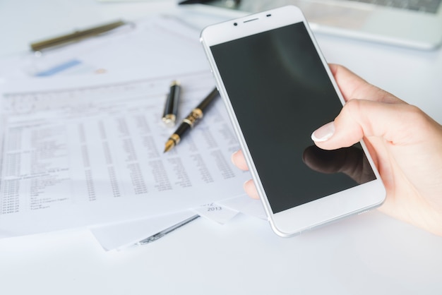 Free photo hand holding smartphone at workplace