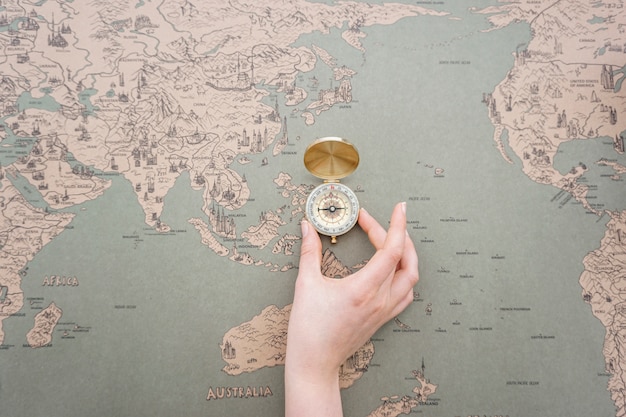 Free photo hand placing a compass on a world map