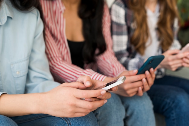 Free photo hands of seated people holding phones