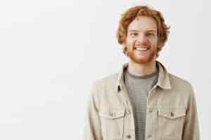 Free photo handsome bearded redhead guy posing against the white wall