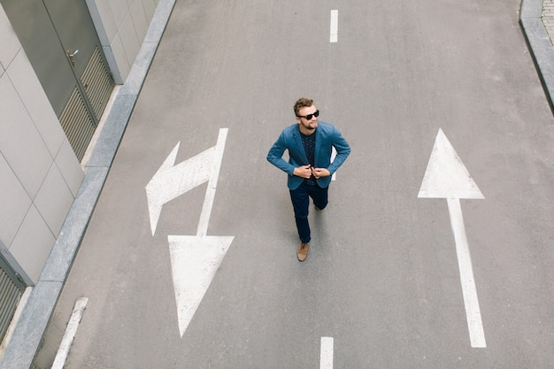 Free photo handsome man in sunglasses is walking on road