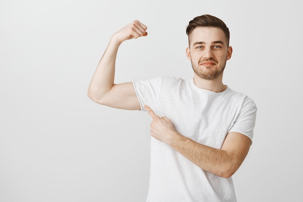 Free Photo handsome young man show-off his strength going gym to workout, flexing muscles and smiling proud