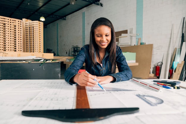 Free photo happy african-american lady with big ruler and pen at table