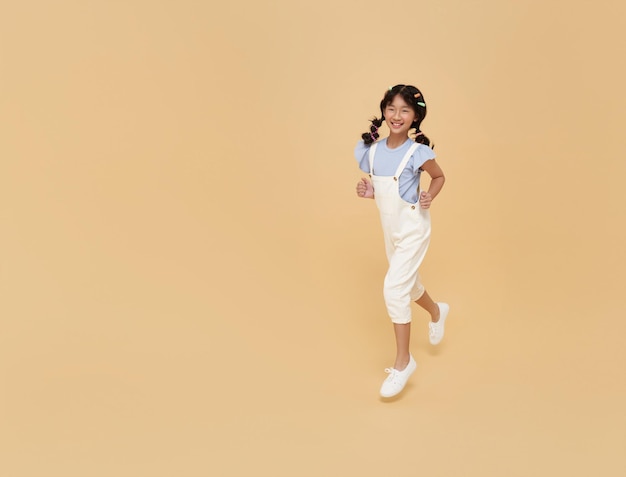 Free Photo happy asian children girl attractive pretty running isolated on nude color copy space background