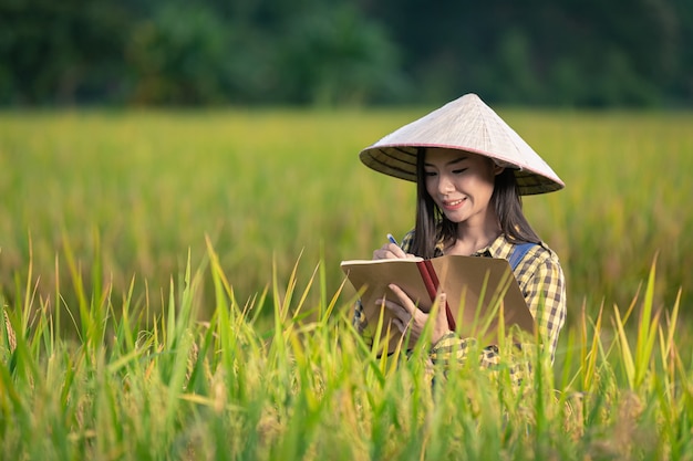 Free photo happy asian female write notes in rice fields