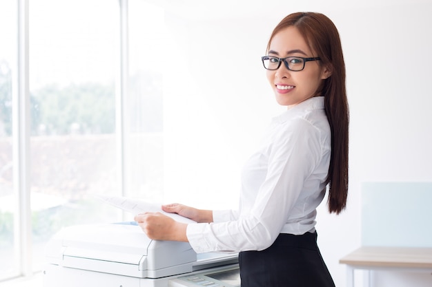 Free photo happy asian lady using multifunction printer