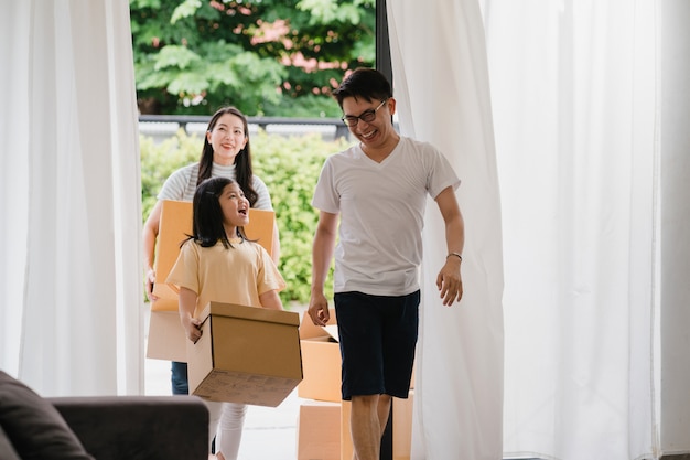 Free photo happy asian young family bought new house. japanese mom, dad, and child smiling happy hold cardboard boxes for move object walking into big modern home. new real estate dwelling, loan and mortgage.