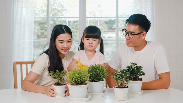 Free photo happy cheerful asian family dad, mom and daughter watering plant in gardening near window at house