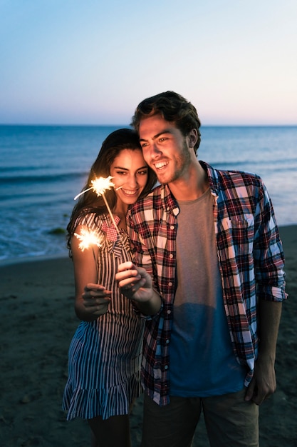 Free photo happy couple with sparkler at the beach