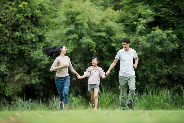 Free photo happy family is having fun mother, father and daughter are running in park.