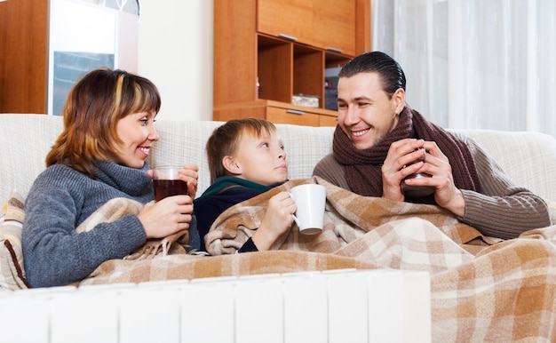 Free photo happy family of three   warming near warm radiator