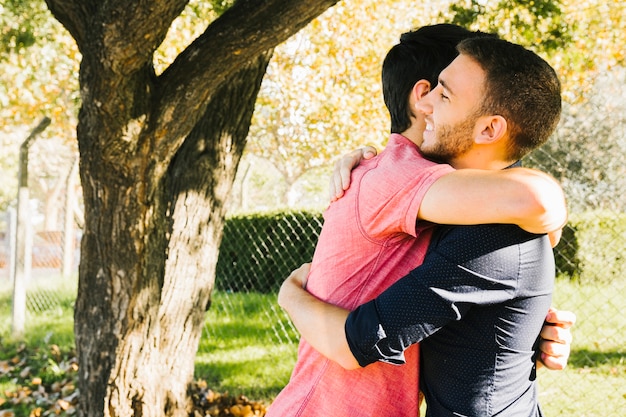 Free photo happy gay couple embracing in park