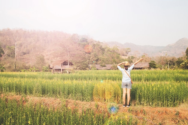 Free photo happy girl traveler standing in flowers field, summer vacation