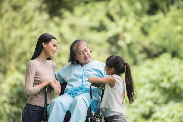 Free photo happy grandmother in wheelchair with her daughter and grandchild in a park, happy life happy time.