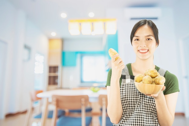 Free photo happy lady holding kitchen stuff over copy space background