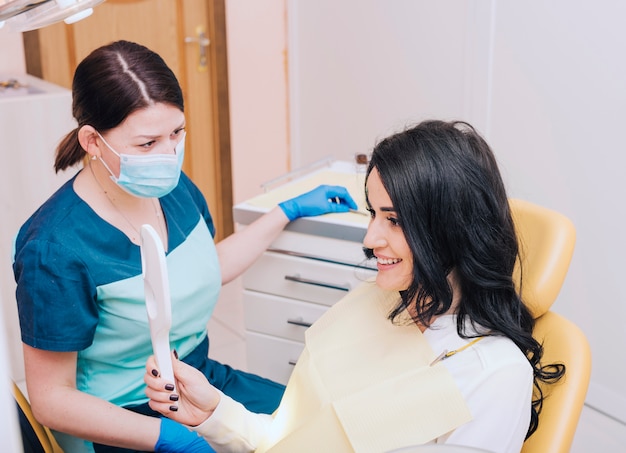 Foto gratuita paziente felice che esamina specchio in studio dentistico