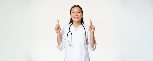 Foto gratuita medico sorridente felice della donna asiatica del medico che osserva in su con l'espressione allegra del fronte che porta medico