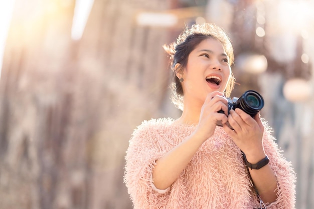 無料Photo 幸せな旅行のクローズアップアジアの女性の手がカメラの旅行者をキャプチャする有名なランドマーク建築の背景を持つアジアの写真家がカメラの休暇の概念で旅行する