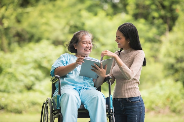 Happy Woman in a wheelchair reading a book with her daughter at the park