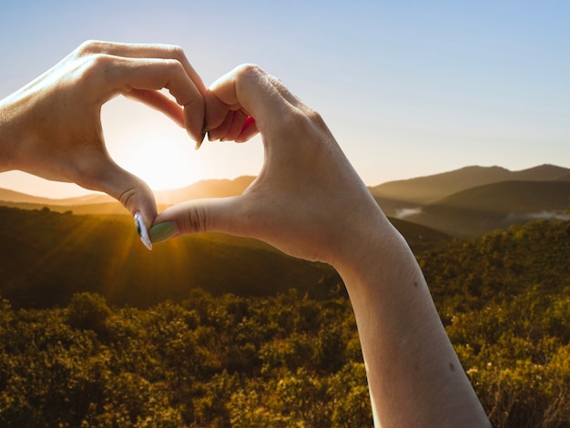 Foto gratuita mani a forma di cuore su un tramonto