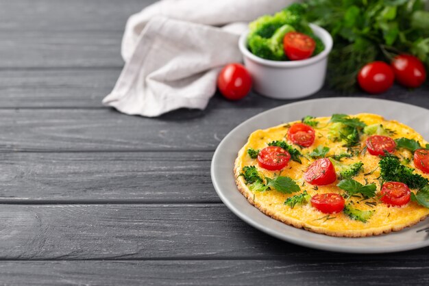 High angle of breakfast omelette on plate with tomatoes and broccoli