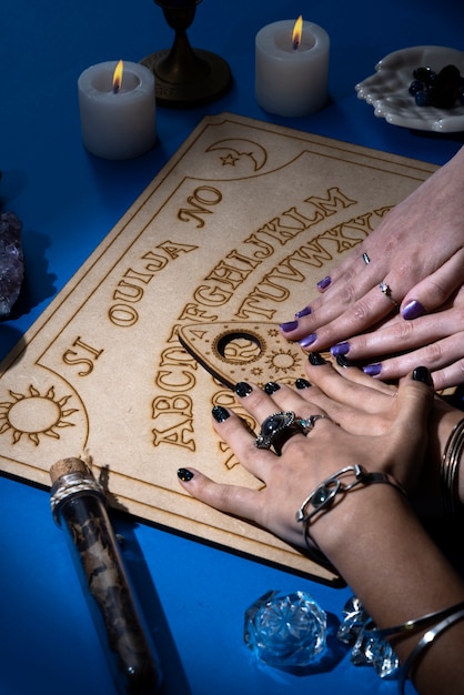 Free photo high angle hands touching ouija board