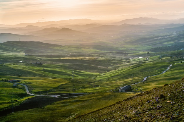 Free Photo high angle shot of an isolated building in a green field surrounded by high mountains