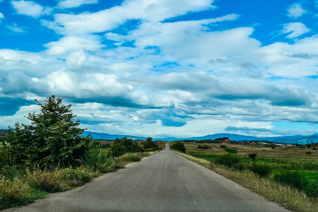 Free photo high angle shot of a road in the valley under the sky with big white clouds