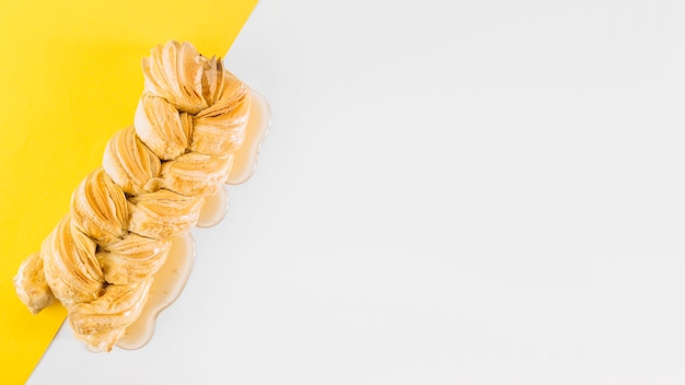 Free photo high angle view of braided strudle and honey on white and yellow background