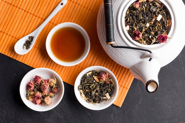 Free photo high angle view of dry herb in ceramic bowl with teapot