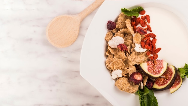 Free photo high angle view of healthy breakfast on plate near wooden ladle over white backdrop