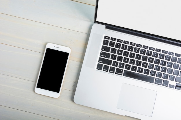 Free photo high angle view of laptop and mobile phone on wooden desk