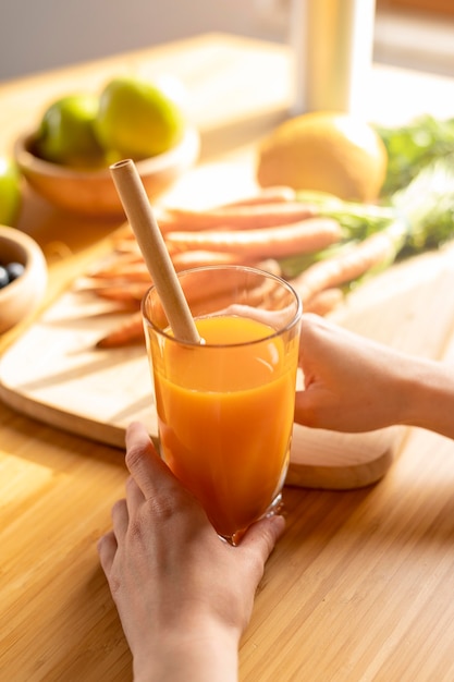 Foto gratuita la donna dell'angolo alto passa il vetro della tenuta con il succo di carota